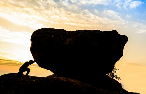 Mann schiebt Steinbrocken an