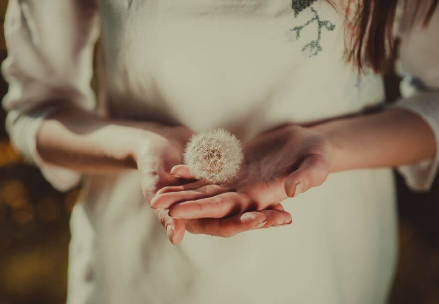 Frau mit Loewenzahn in der Hand