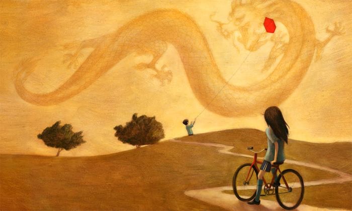 Maedchen auf Fahrrad schaut zu Junge mit Drachen
