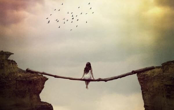 Frau sitzt auf Baumstamm und schaut in den Himmel