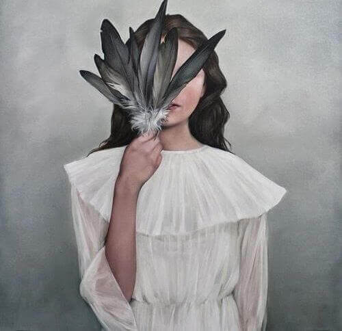 Frau versteckt ihr Gesicht hinter Federn