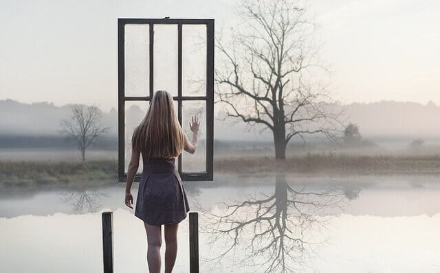 Frau berührt Fenster zum See