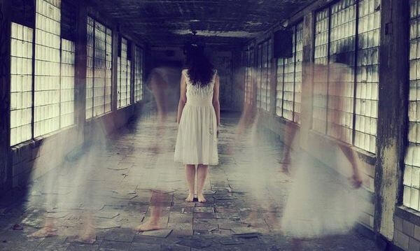 Eine geisterhafte Erscheinung einer Frau wandelt durch einen Korridor.