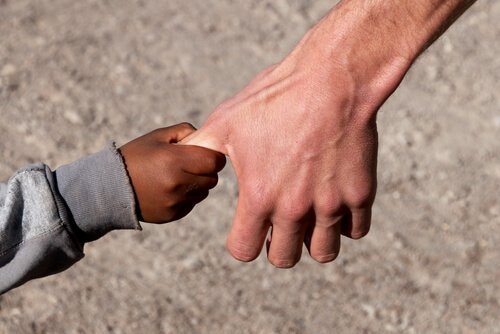 Kinderhand hält sich am Daumen eines Erwachsenen fest