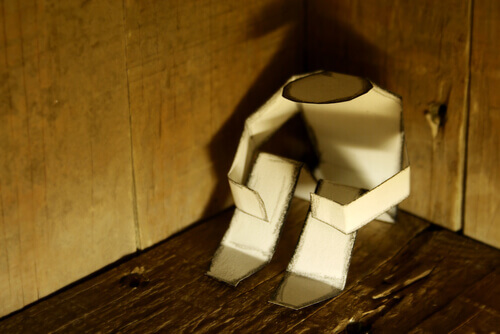 figur-aus-papier-sitzt-in-der-ecke