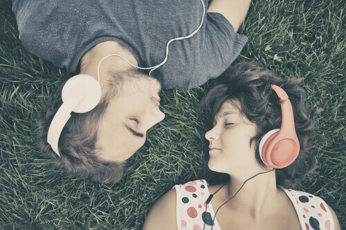 Paar liegt auf der Wiese und hört Musik