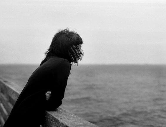 Eine einsame Frau blickt auf das Meer. 