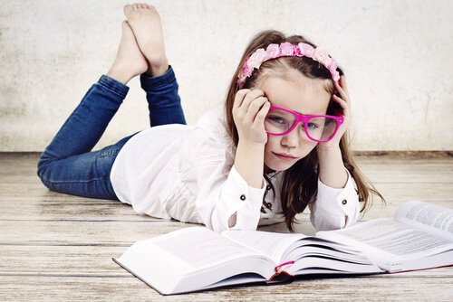 Mädchen mit großer Brille liest zwei Bücher