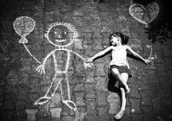Ein Mädchen liegt auf dem Boden und hält Händchen mit einem gezeichneten Kreidemännchen.