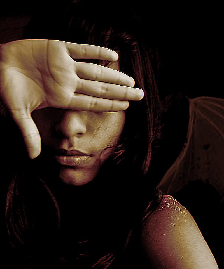 Frau verdeckt mit ihrer Hand ihr Gesicht