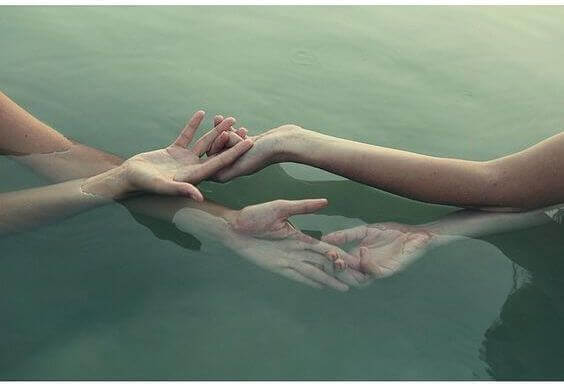 Eine sanfte Berührung der Hände zweier Personen im Wasser