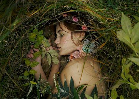 Eine Frau schläft umgeben von Pflanzen