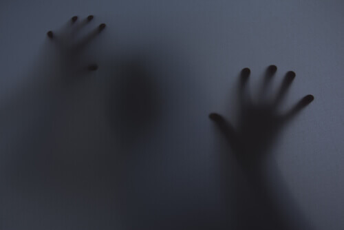 Person berührt eine beschlagene Fensterfläche von hinten.