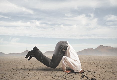 Mann steckt seinen Kopf in vertrockneten Boden