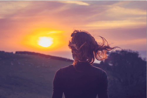 Frau schaut Sonnenaufgang zu