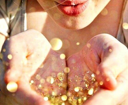 Frau pustet goldenen Glitzer