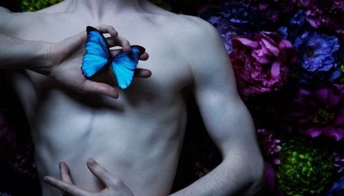Oberkörper eines Mannes, der einen blauen Schmetterling in der Hand hält