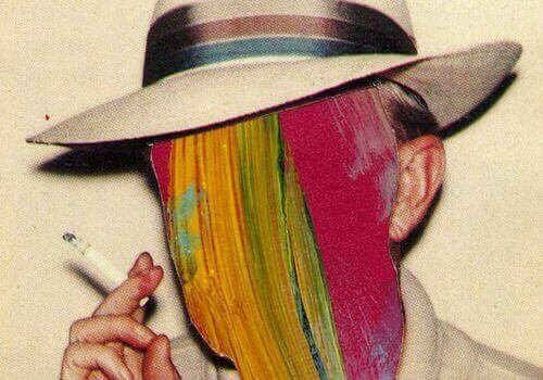 Rauchender Mann mit Hut, dessen Gesicht mit bunten Farben übermalt ist