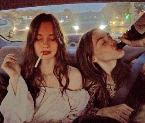 Zwei junge Frauen, die trinken und rauchen