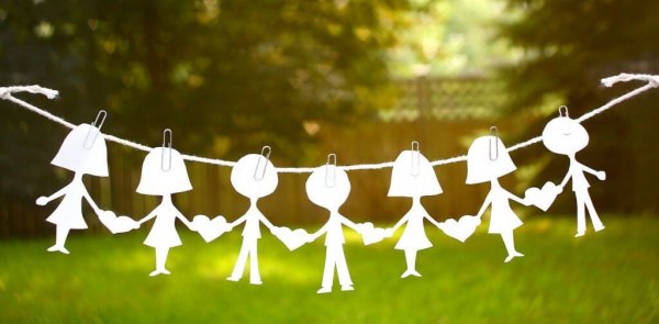 Papiermännchenkette hängt vor einer Gartenlandschaft