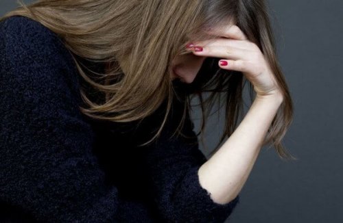 Frau blickt nach unten und fasst sich an den Kopf