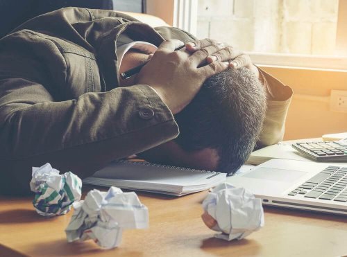 Frustrierter Mann legt den Kopf auf den Tisch