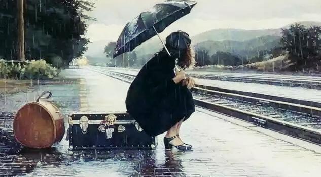 Frau mit Regenschirm wartet am Bahngleis