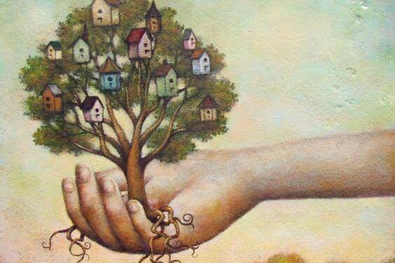 Hand hält einen Baum mit Häuschen in der Baumkrone