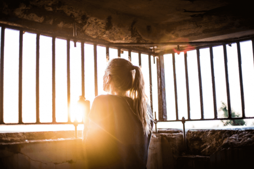 Frau schaut durch ein Gitter zum Licht