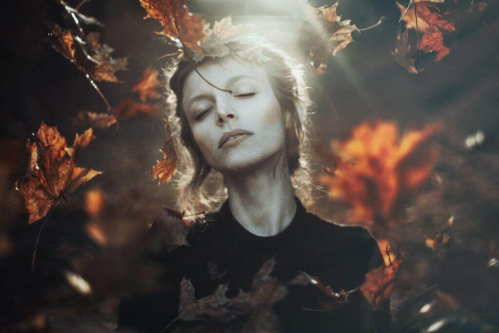 Frau im Herbst umgeben von Blättern