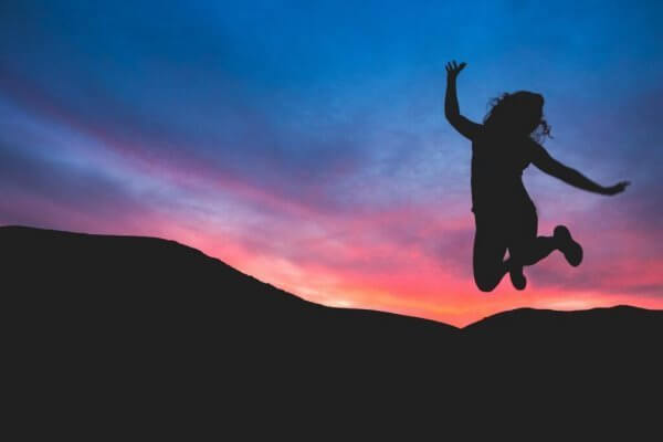 Frau springt vor Sonnenuntergang in die Luft