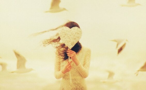 Mädchen versteckt sich hinter einem gebastelten Herz