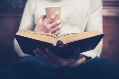 Frau mit Kaffee in der Hand liest ein Buch