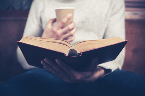 Frau mit Kaffee in der Hand liest ein Buch 