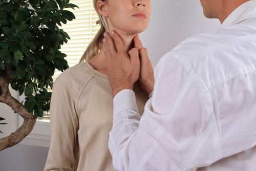 Arzt untersucht die Schilddrüse einer Frau