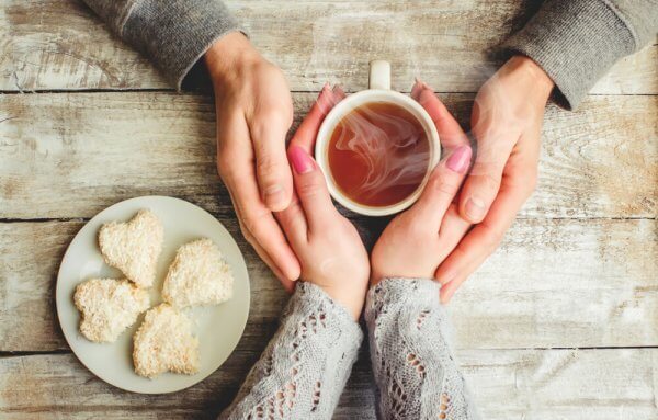 Vier Hände halten eine Teetasse