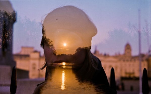 Das Licht der untergehenden Sonne spiegelt sich auf Wasserflächen und im Gesicht einer Frau.