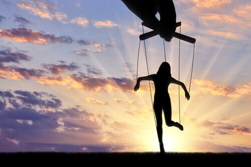 Eine Hand führt eine Marionette vor einem Sonnenaufgang.