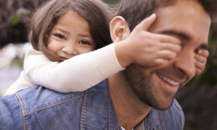 Lachendes Mädchen verdeckt ihrem Vater die Augen