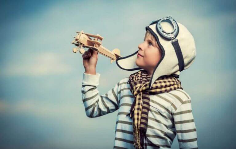 Ein Junge spielt mit einem Flugzeug aus Holz.