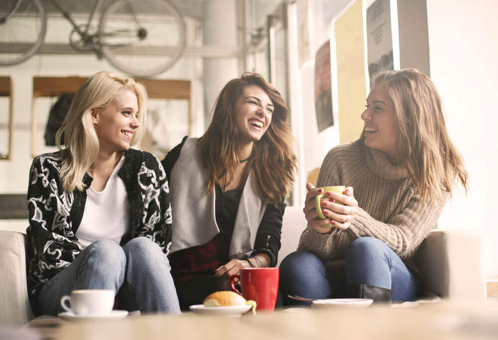 Eine Gruppe von Freundinnen sitzt zusammen und trinkt Kaffee. Alle sind positiv gestimmt.