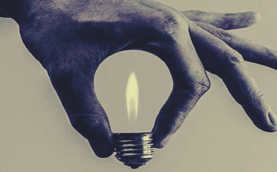 Eine Hand formt eine Glühbirne mit Flamme