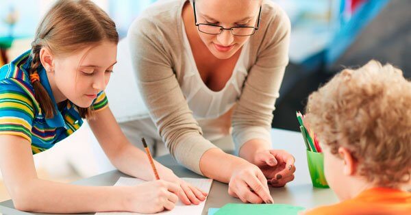 Eine Lehrerin erklärt zwei Schülern den Unterrichtsstoff.