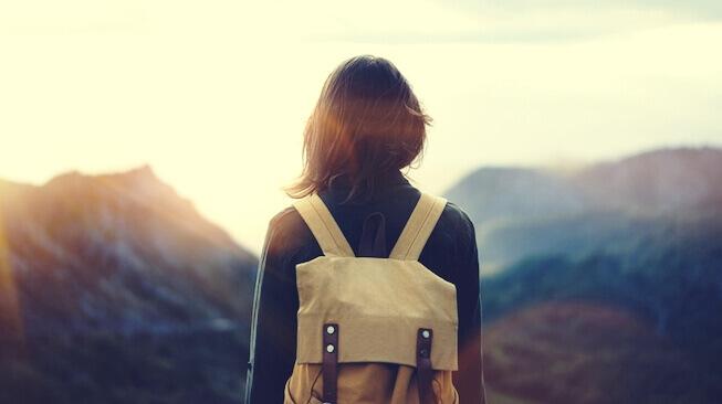 Frau mit Rucksack schaut auf Berge