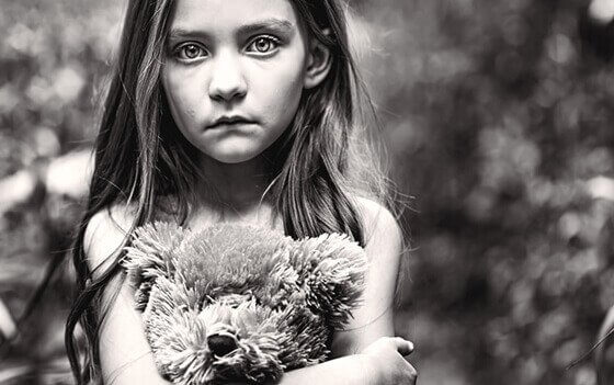 Ein trauriges Mädchen drückt ihren Teddybär. 
