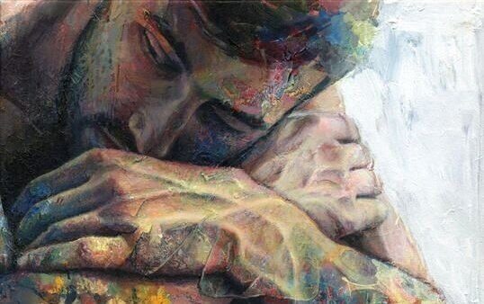 Ein Mann legt seinen Kopf auf seinen Armen ab. Er wirkt depressiv.