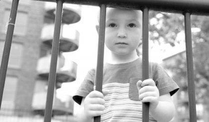 Junge, der hinter einem Gitter steht