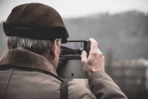 Älterer Herr, der mit dem Smartphone ein Foto macht