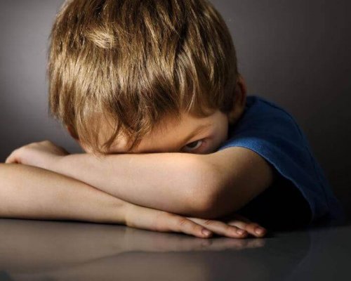 Junge, der sein Gesicht in den Armen versteckt