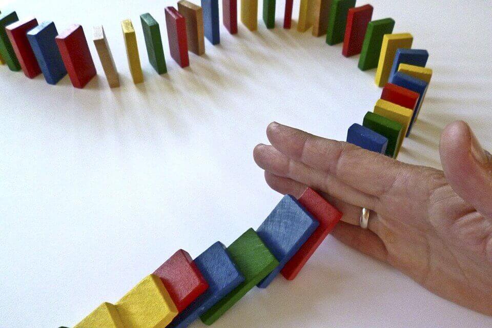 Bunte Dominoschlange wird von einer Hand unterbrochen